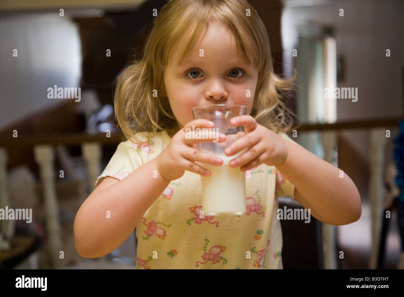 Three-year-old girl drinking milk from a glass. Stock Photo