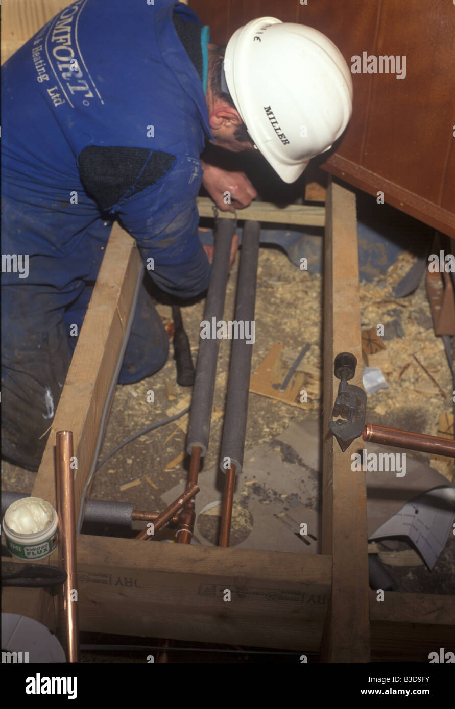A plumber fits insulation to plumbing in a new house Stock Photo