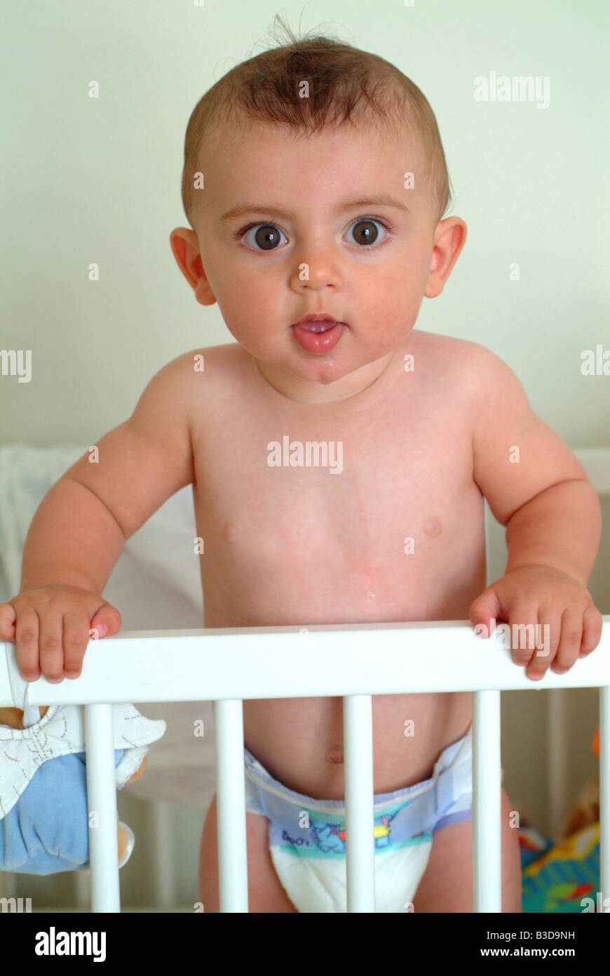 cute baby boy standing in his cot in his bedroom at home Stock Photo