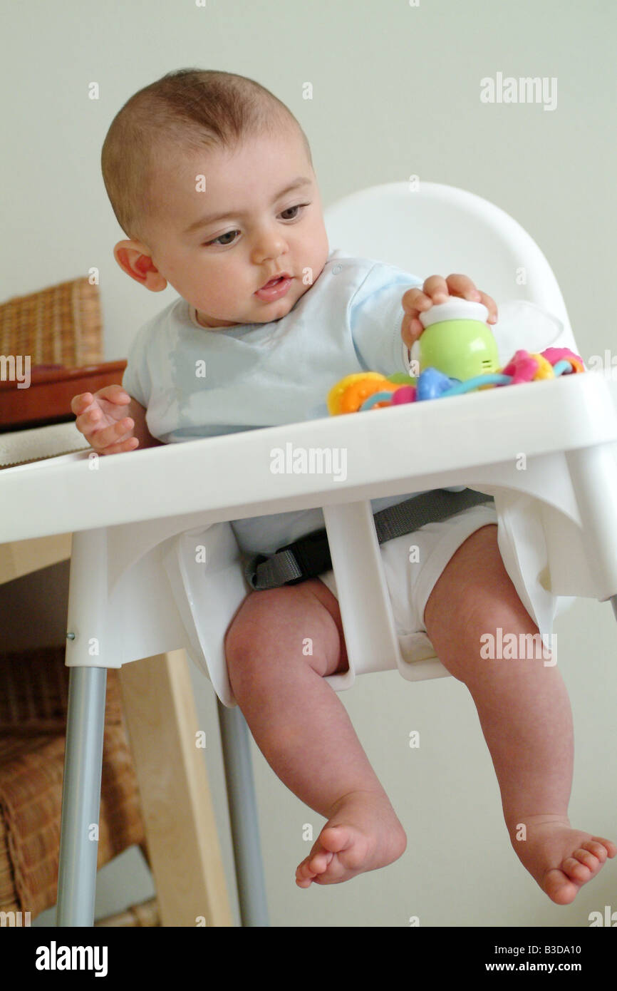 baby boy sitting in highchair playing with a toy Stock Photo Alamy