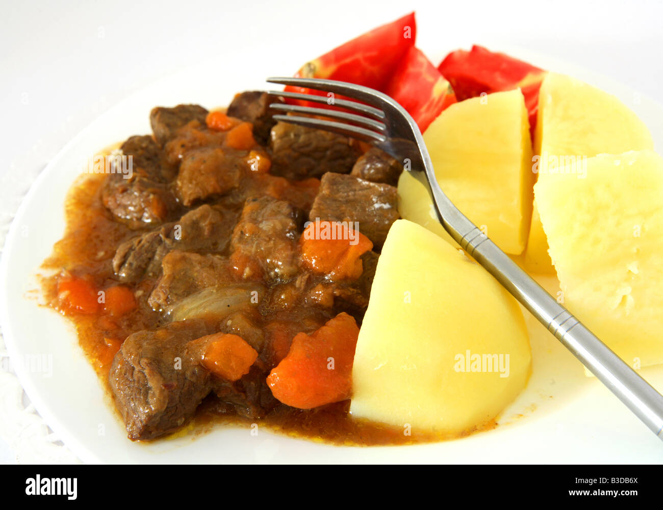 A beef stew with carrots and onion boiled potatoes and tomato wedges