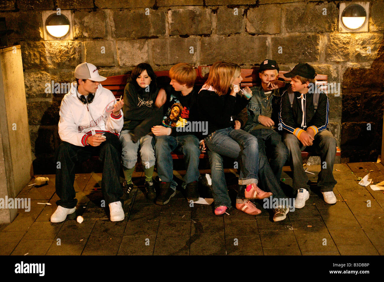 Teenagers sitting on a bench at night, Reykjavik, Iceland Stock Photo