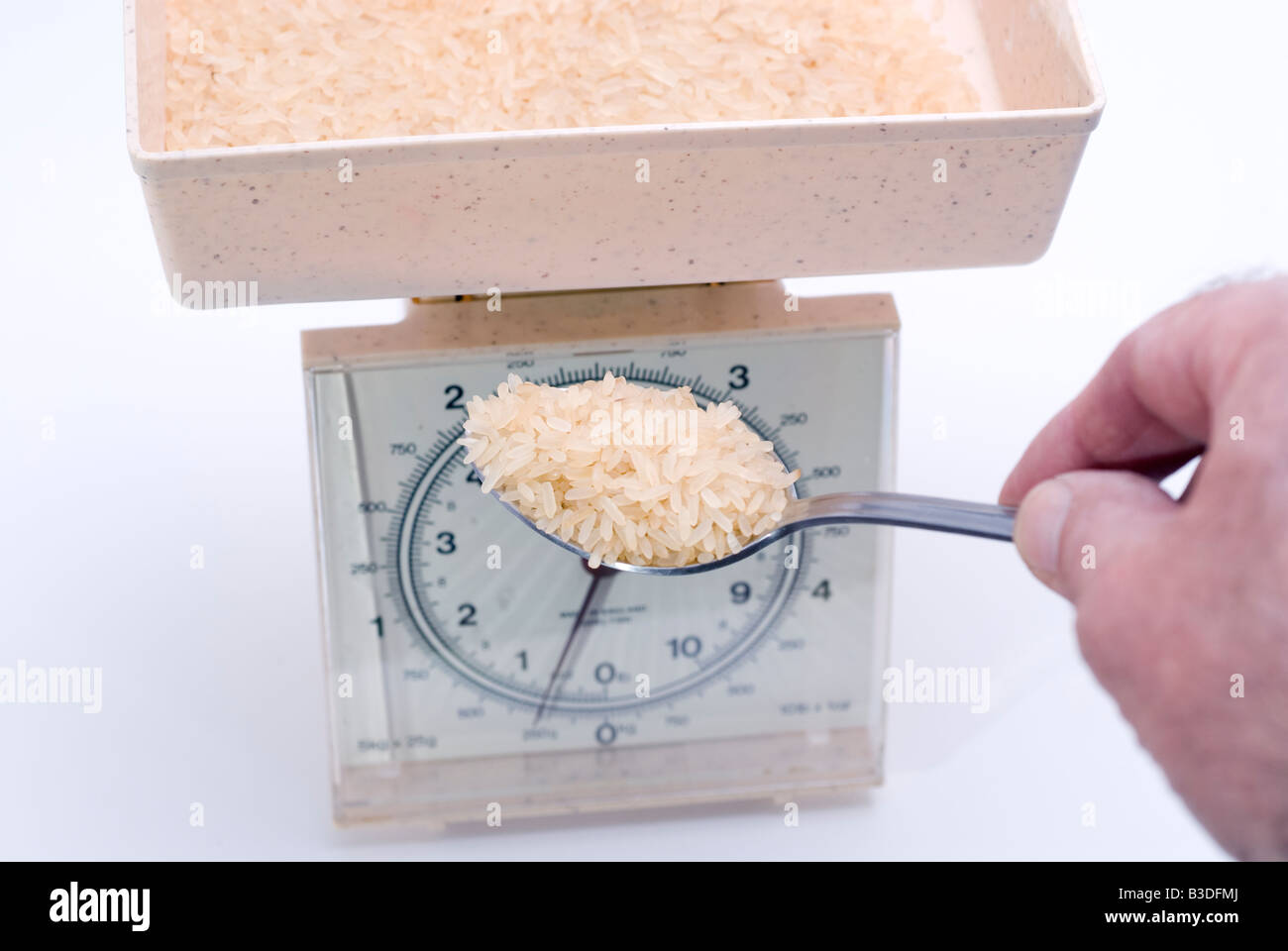 Heaped tablespoon of long grained rice being placed on kitchen scales