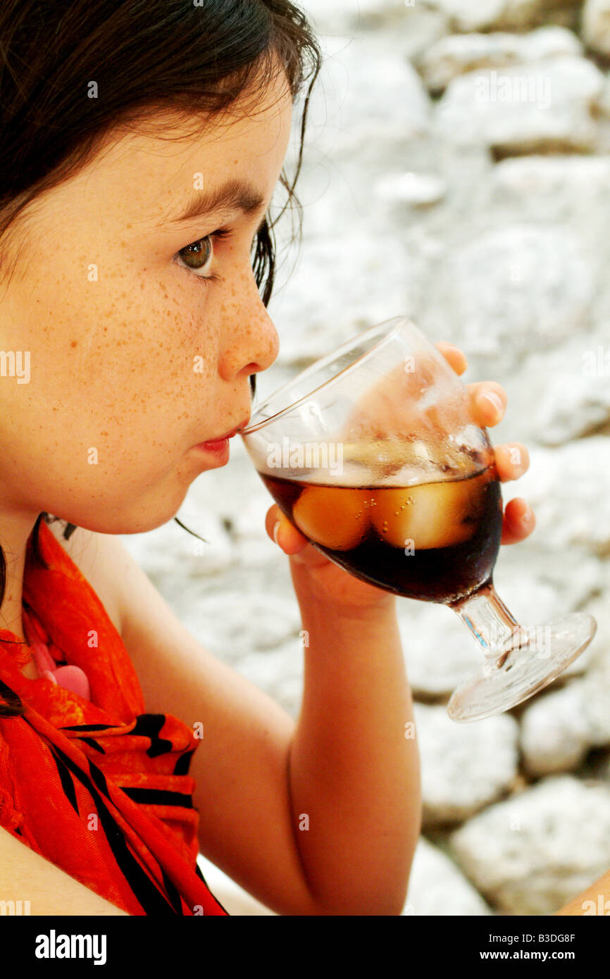 a pretty brunette drinks from a glass of coke in summer Stock Photo