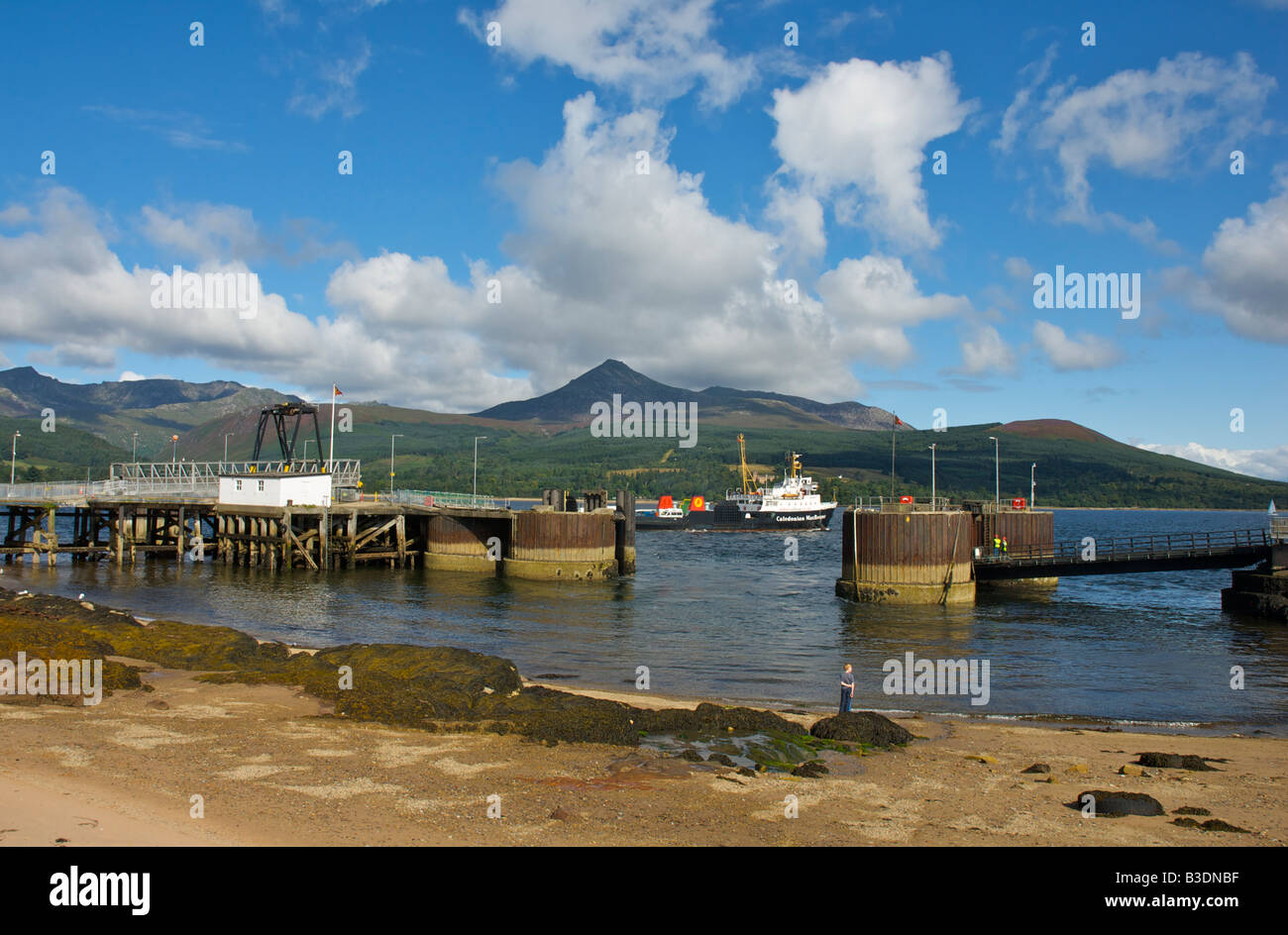 Car ferry leaving the quayside at Brodick, Isle of Arran, Strathclyde, Scotland UK, with view across Brodick Bay to Goat Fell Stock Photo