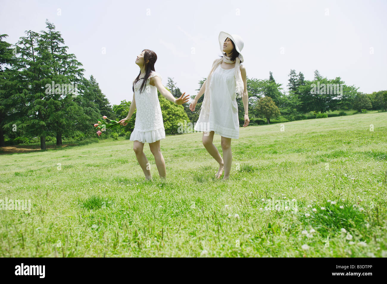 Two young women walking in park Stock Photo - Alamy