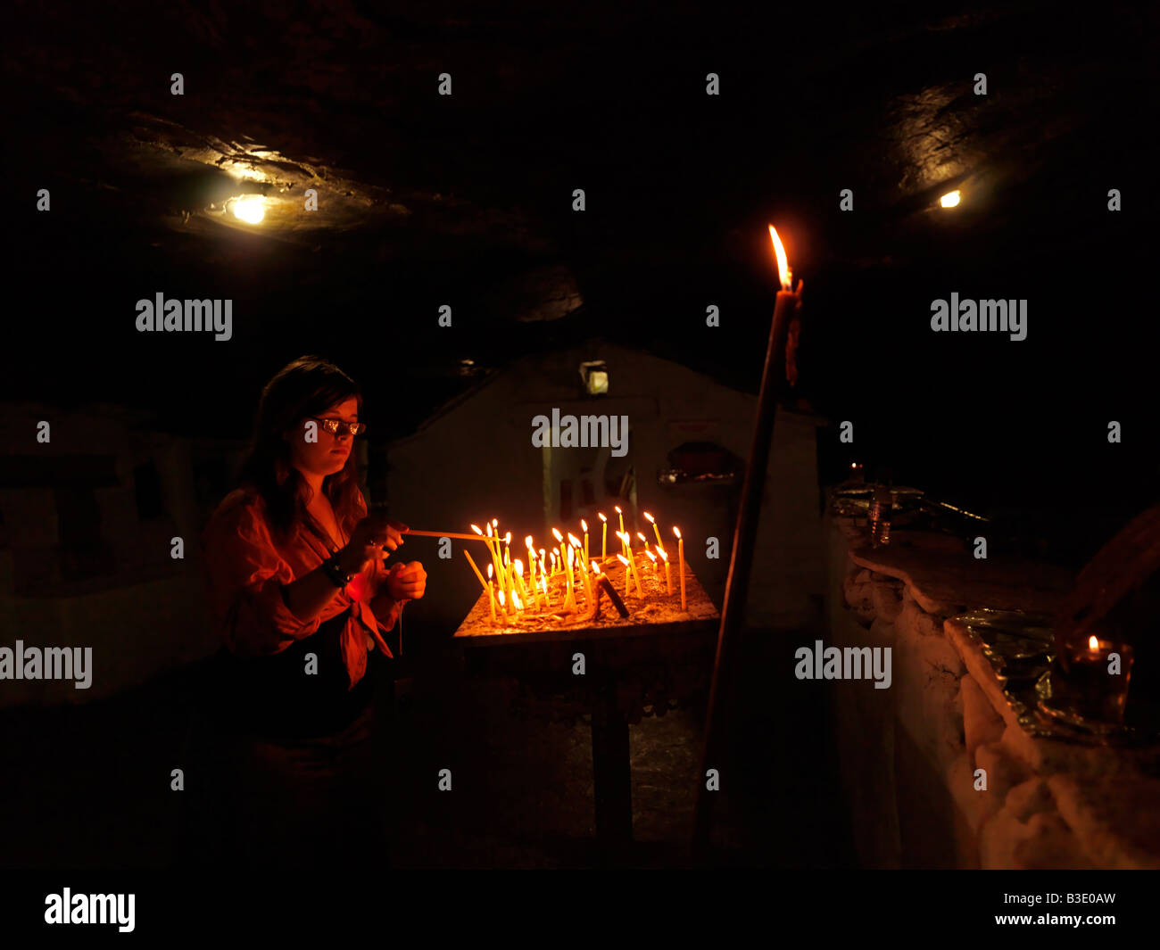 Teenager Lighting Candle at the Underground Cave Church Spiliani Monastery Samos Greece Stock Photo