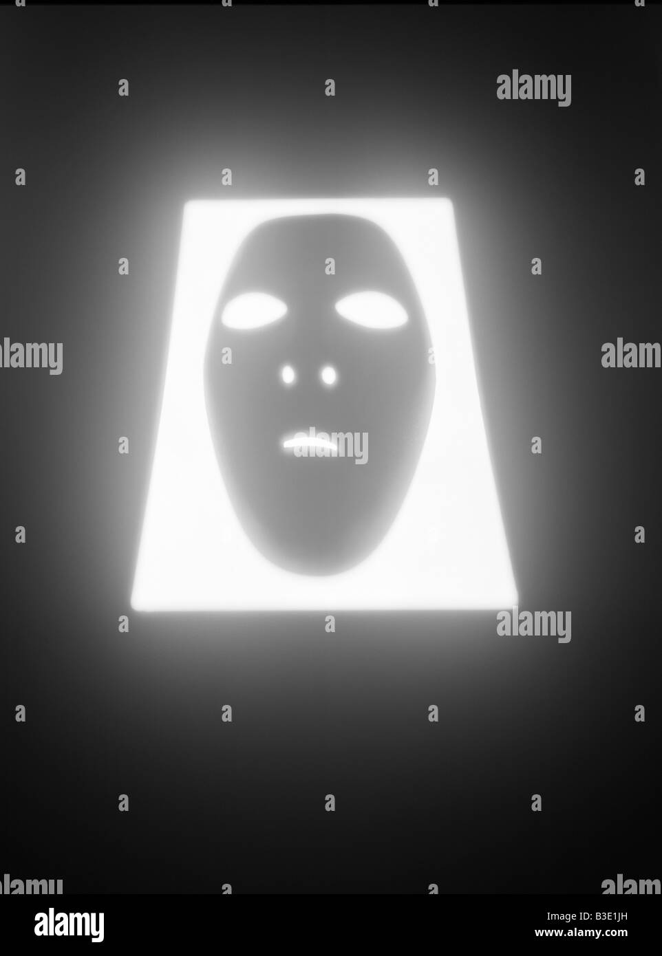 A  human face mask glowing in a rectangular shaped hole Stock Photo