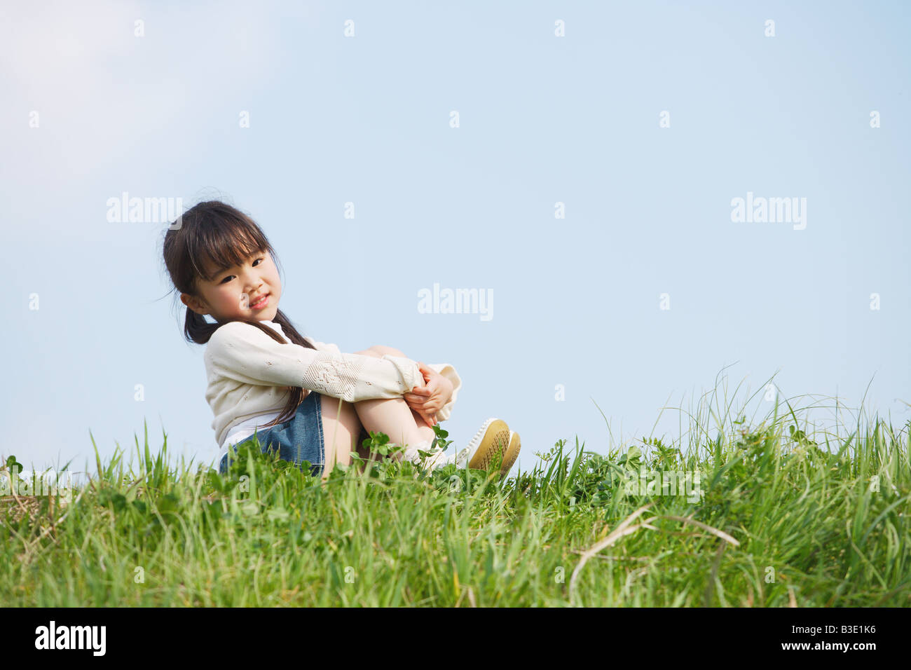 Girl sitting in park and looking at camera Stock Photo - Alamy