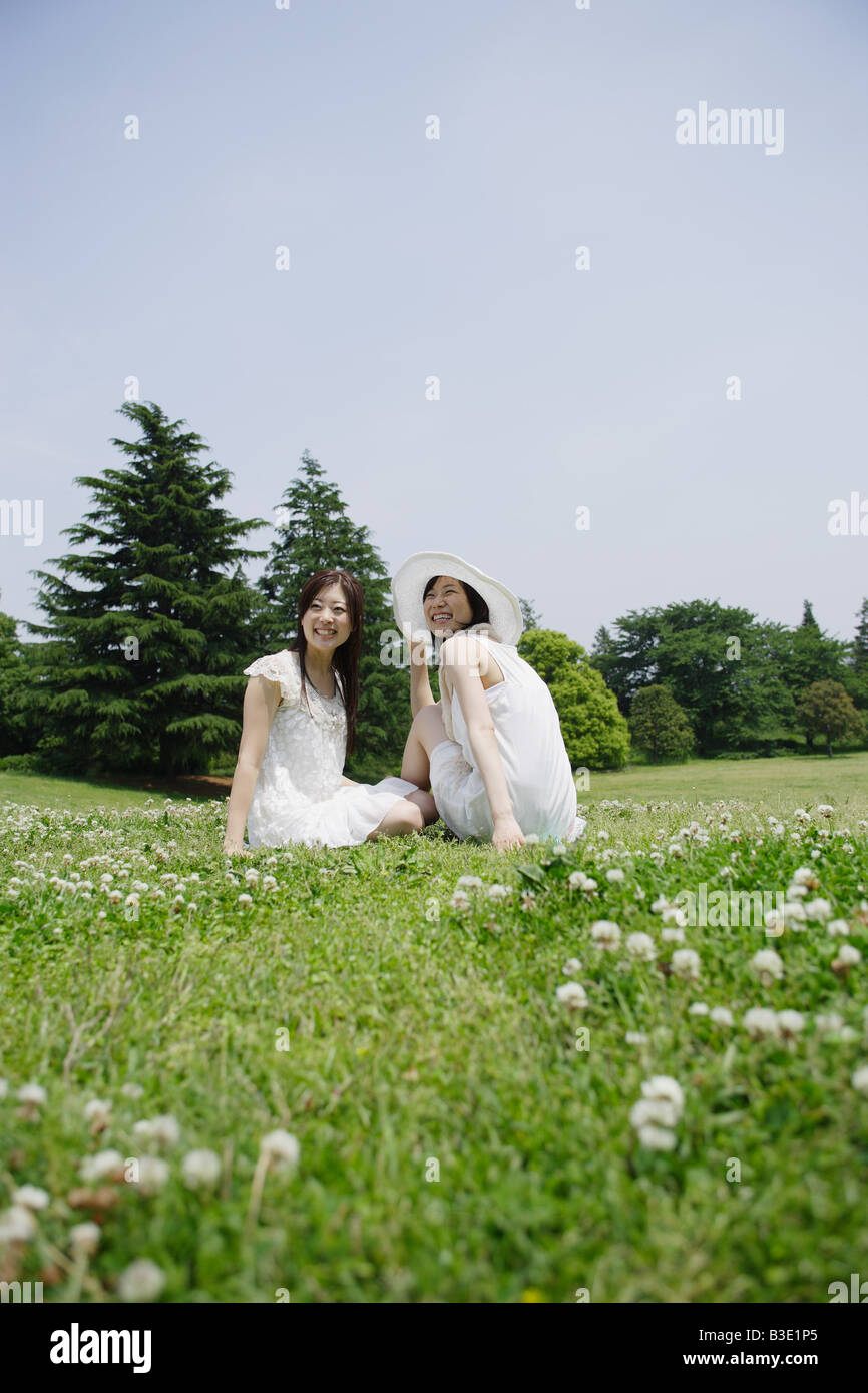 Two young women sitting in park Stock Photo - Alamy
