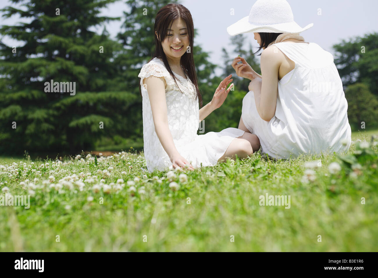 Two young women sitting in park Stock Photo - Alamy
