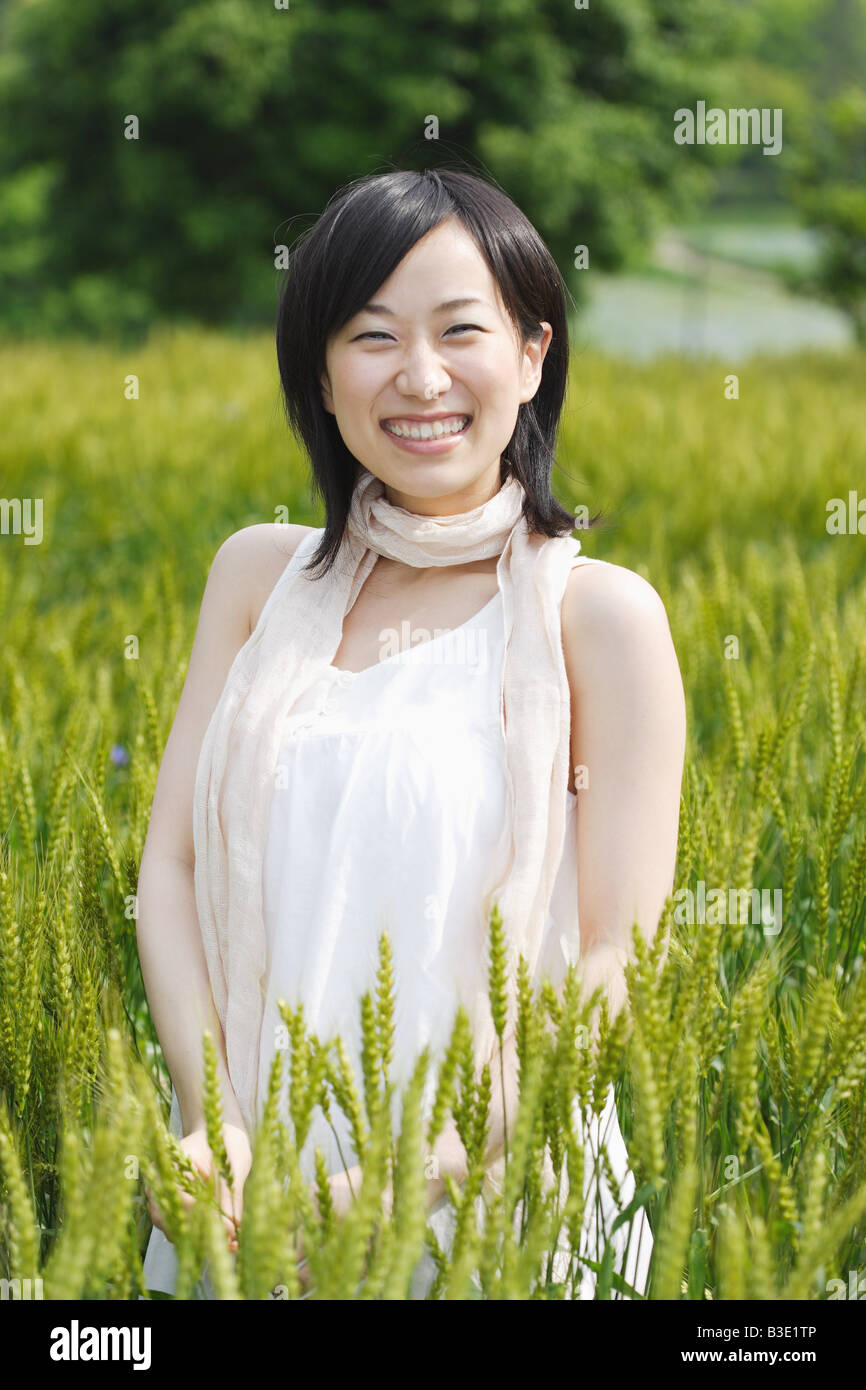Smiling young woman standing in wheat field Stock Photo