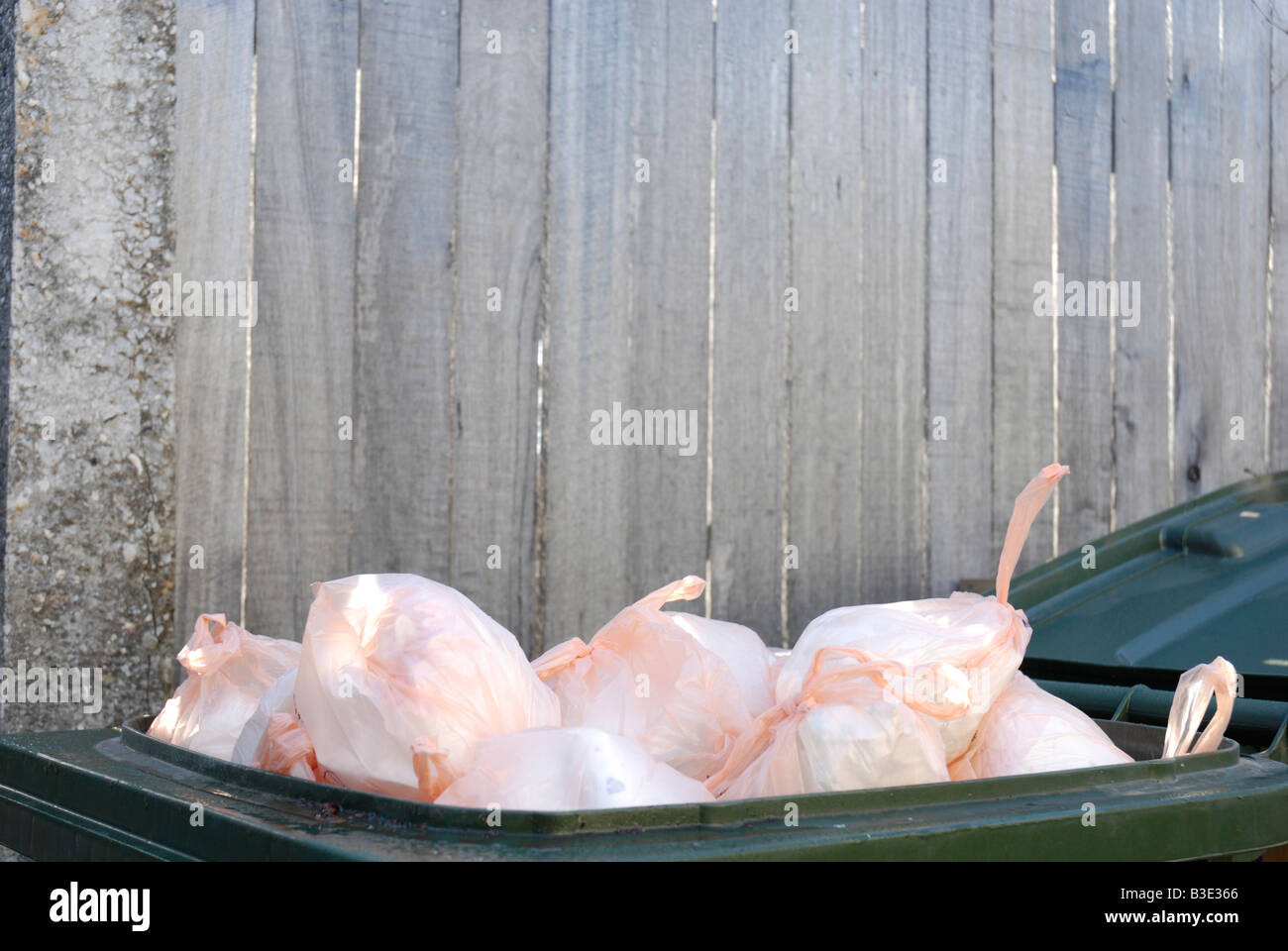 Used disposable nappies in plastic sacks fill a household waste bin
