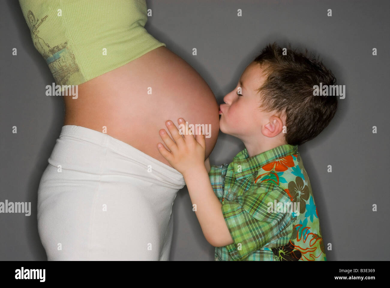 BOY KISSING THE BELLY OF HIS PREGNANT MOTHER Stock Photo