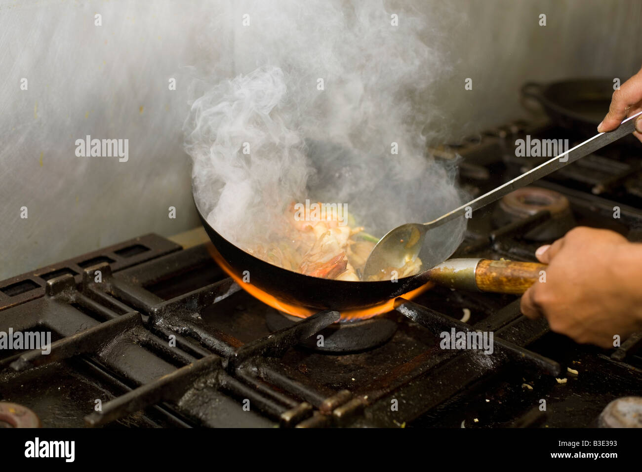 A chef pan frys pawns in an Indian restaurant Stock Photo