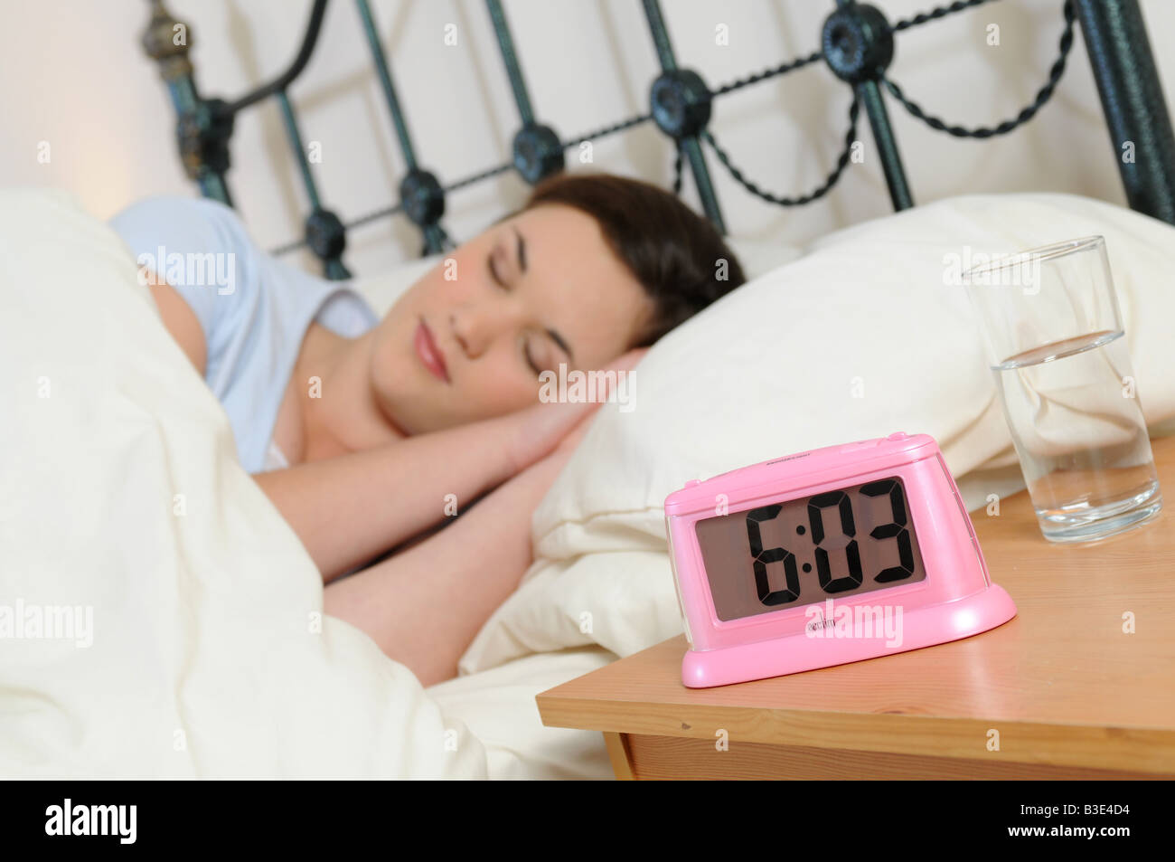a girl sleeping in bed next to her alarm clock Stock Photo