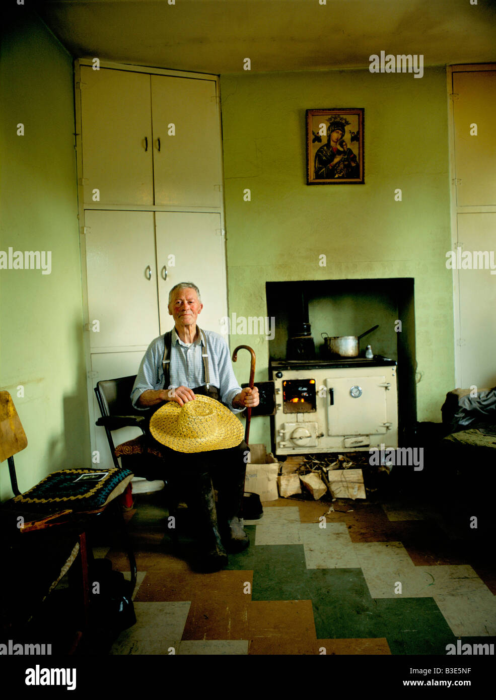 A FARMER ON THE DINGLE PENINSULA IN SOUTHERN IRELAND POSES INSIDE HIS COTTAGE WITH HIS STOVE ON BEHIND HIM PROVIDING HEAT Stock Photo