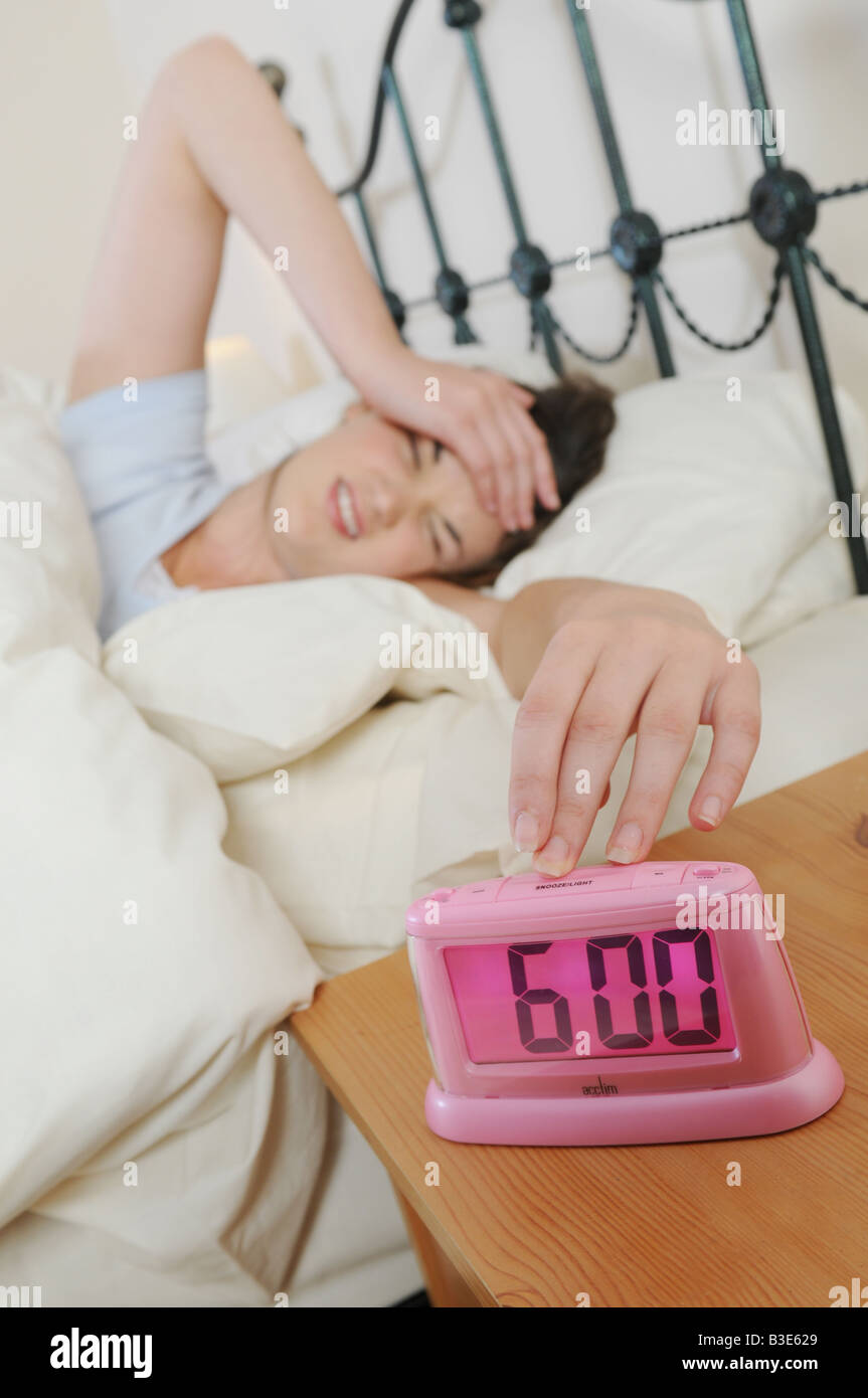 a girl woken up in bed by her alarm clock Stock Photo