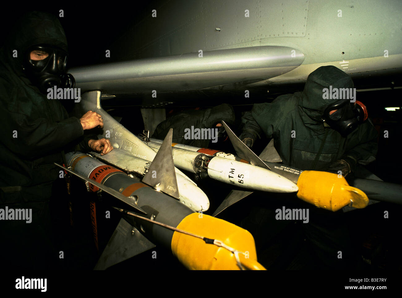 GROUND CREW WEARING GAS MASK NBC NUCLEAR BIOLOGICAL CHEMICAL PROTECTIVE SUITS LOADING MISSILES ONTO PHANTOM JET FIGHTER Stock Photo