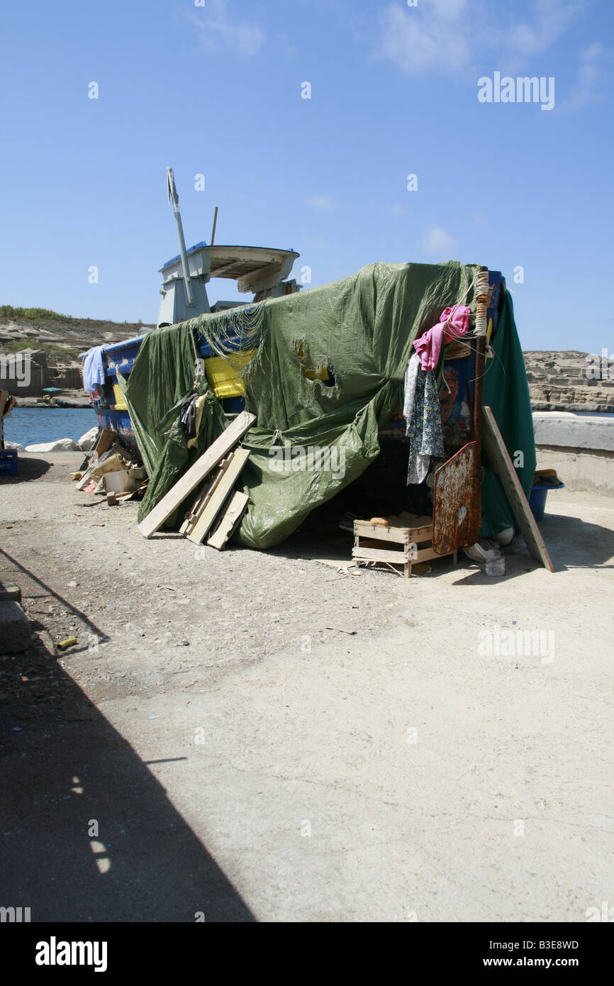 https://c8.alamy.com/comp/B3E8WD/old-fishing-boat-with-tarpaulin-cover-on-dry-land-in-sun-B3E8WD.jpg