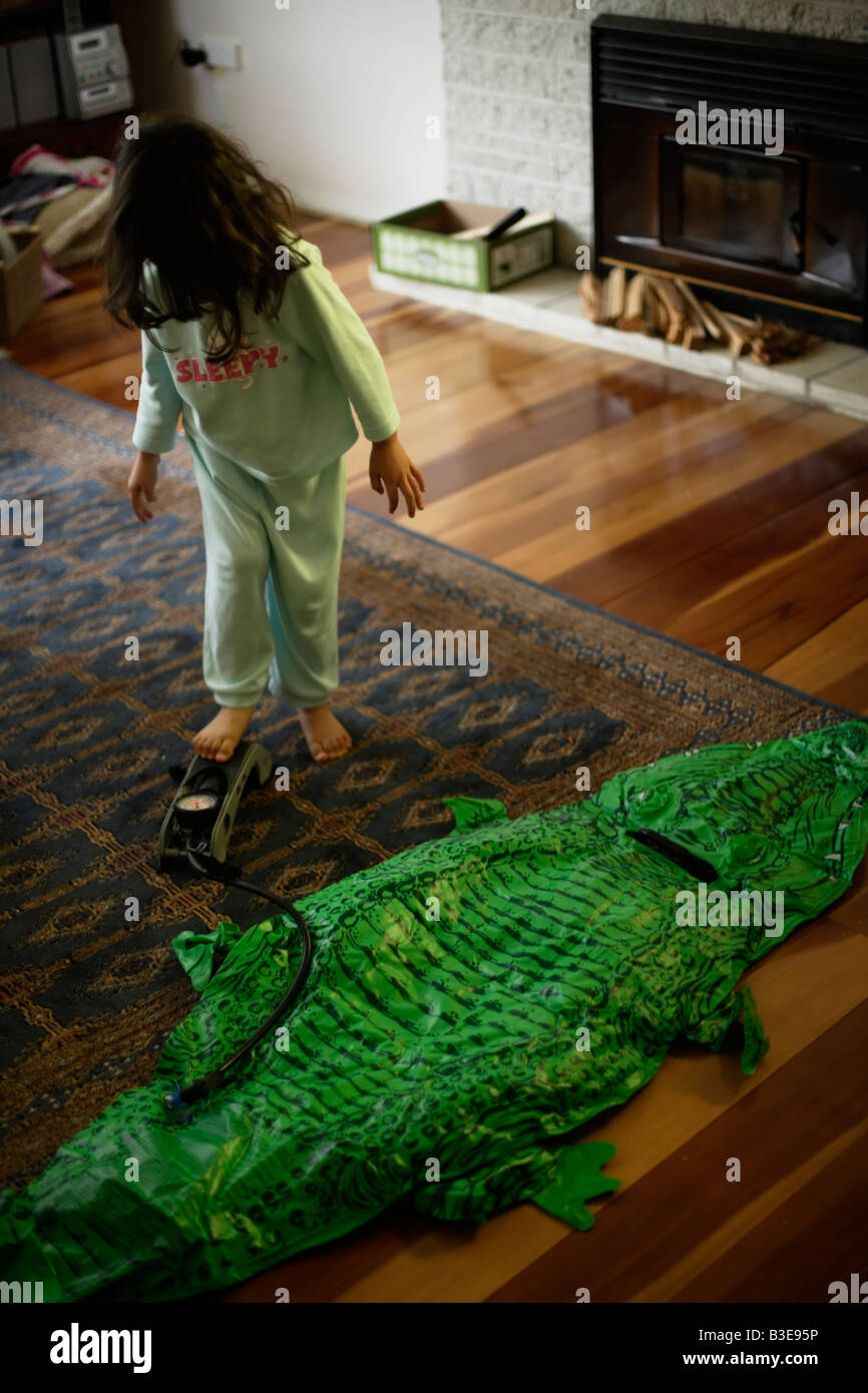 Inflatable crocodile series. Girl aged five blows up crocodile Stock Photo