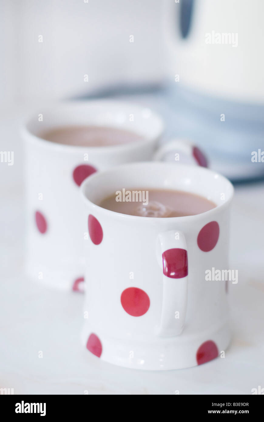 Red polka dot tea mugs with kettle in background Stock Photo