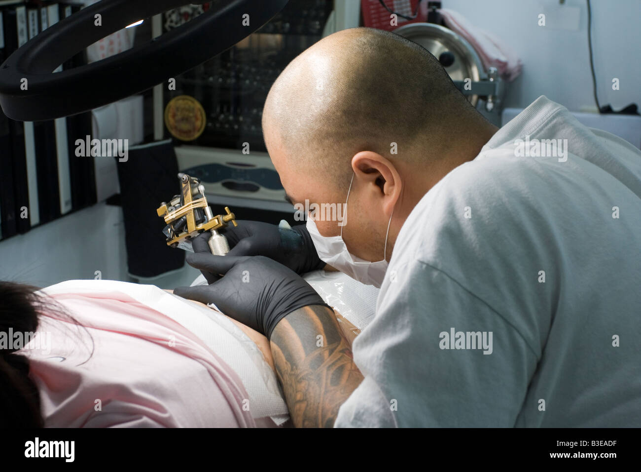 Young female Taiwanese Chinese receiving lower back tattoo from Asian male with shaved head, Taipei Taiwan Republic of China ROC Stock Photo