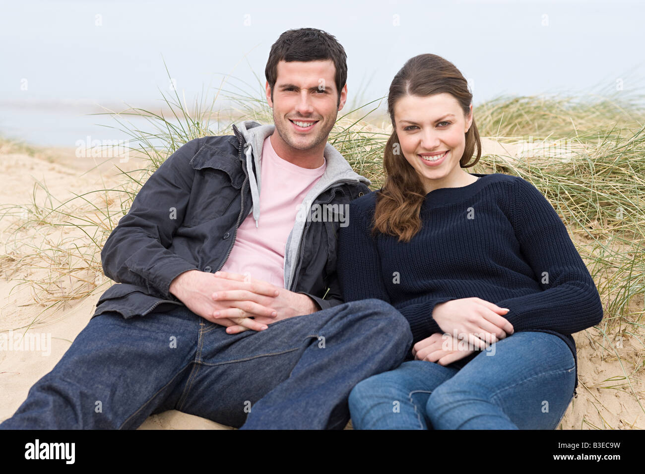 Couple sitting on a sand hill at beach Stock Photo