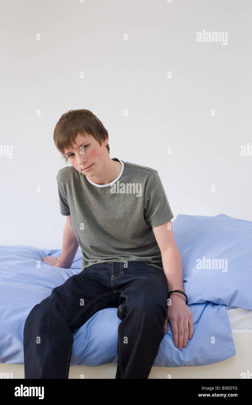 Portrait of a teenage boy sat on a bed Stock Photo - Alamy