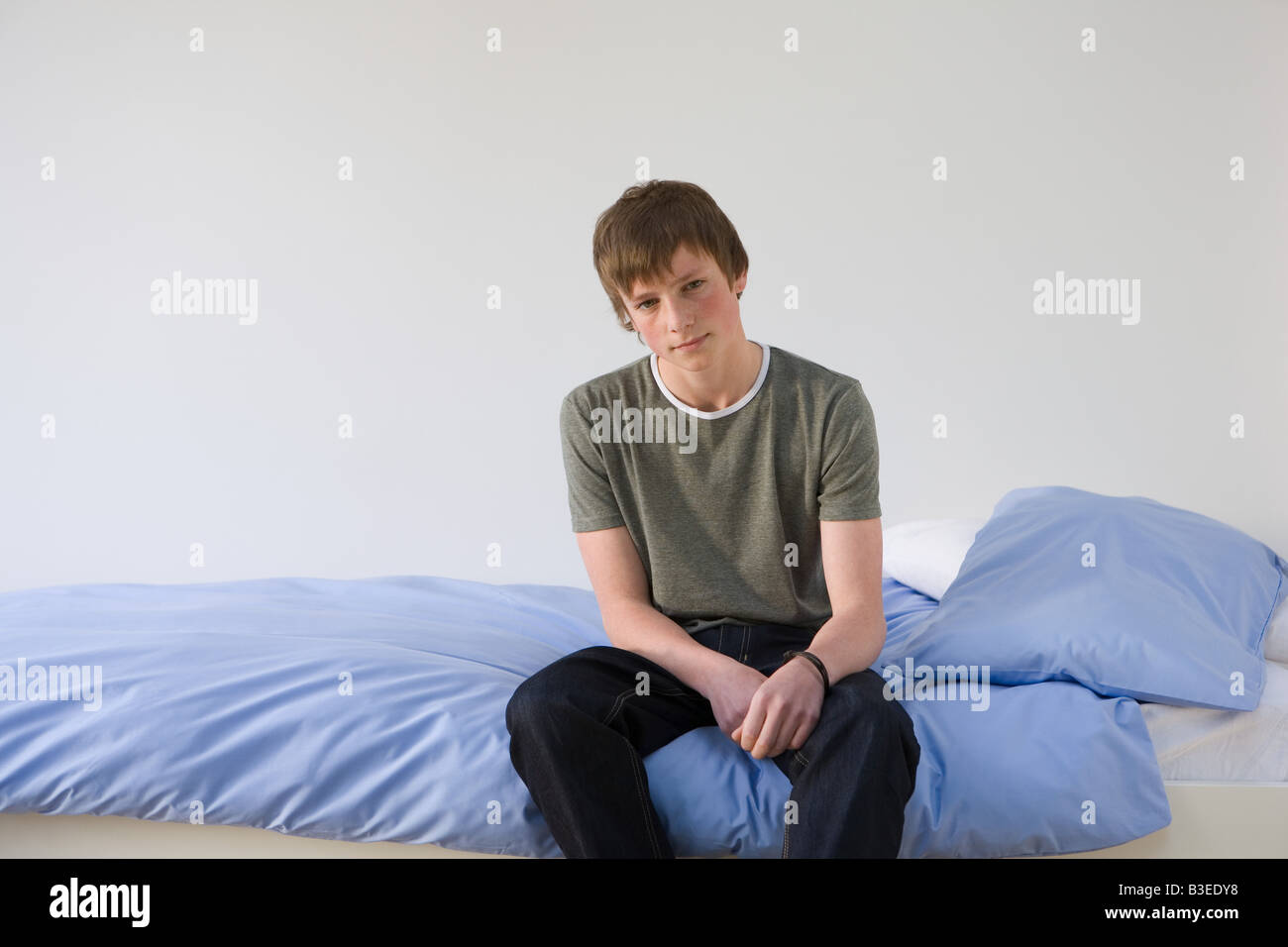 Portrait of a teenage boy sat on his bed Stock Photo - Alamy