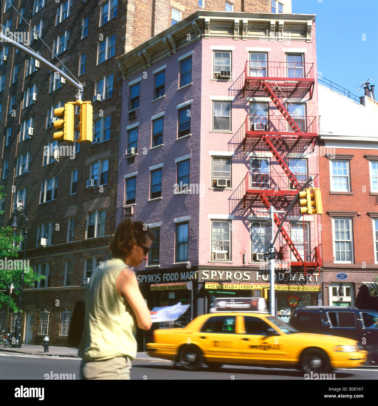 A woman pedestrian and street scene near 8th Ave and Bleecker Street with red fire escape and yellow taxi cab NYC  KATHY DEWITT Stock Photo