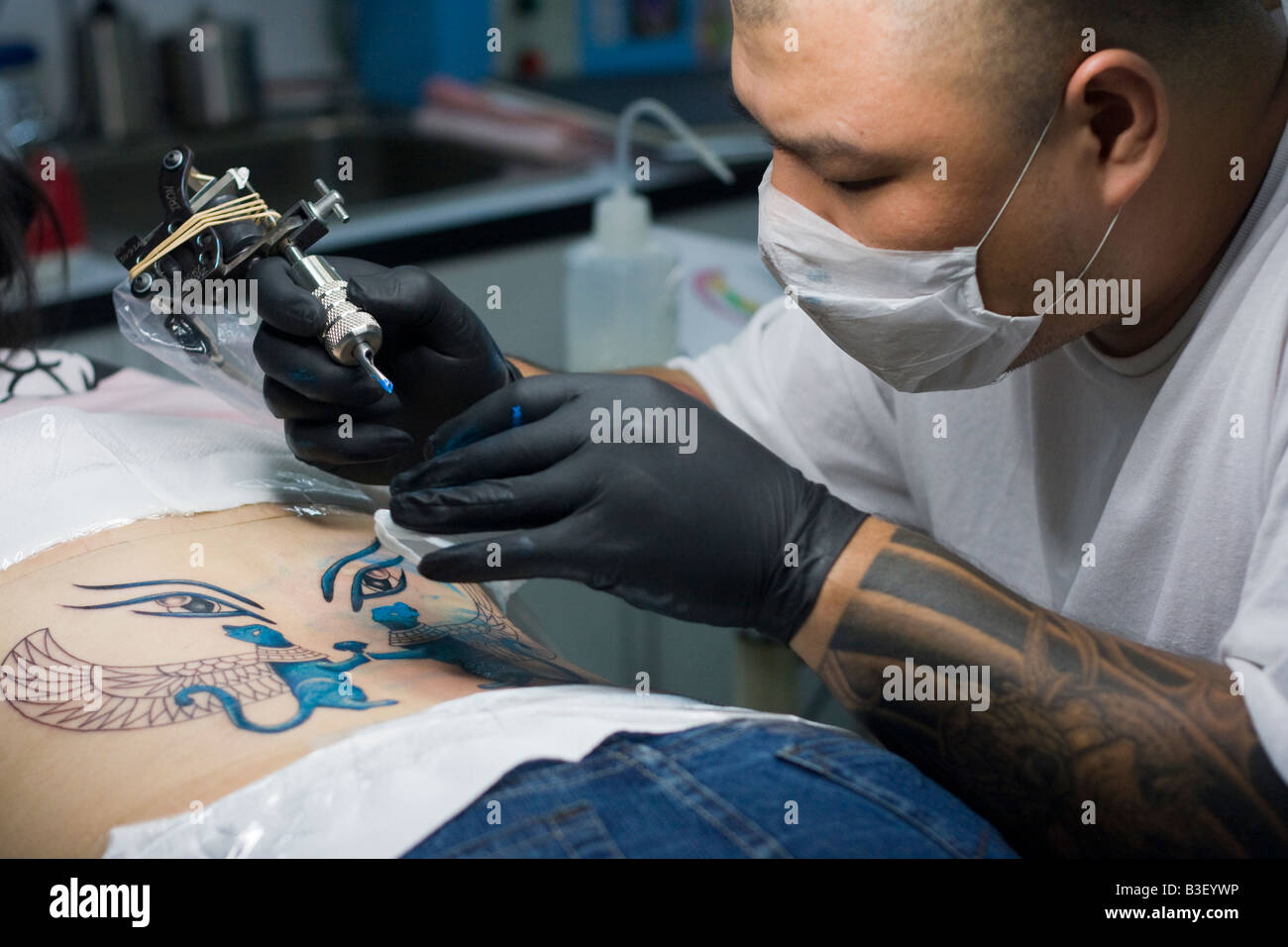 Young female Taiwanese Chinese receiving lower back tattoo from Asian male with shaved head, Taipei Taiwan Republic of China ROC Stock Photo