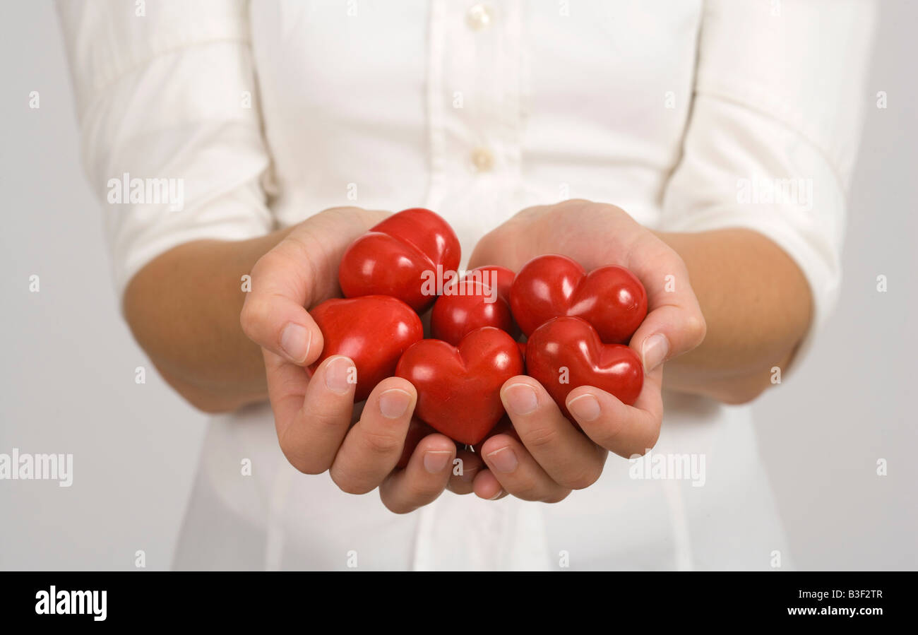 Frauenhand hält mehrere rote Herzen Stock Photo