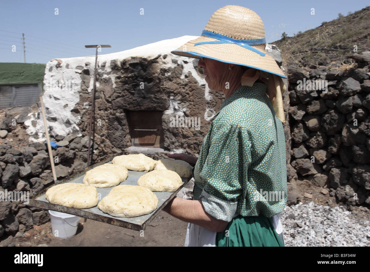 A woman holds a tray of dough ready to be placed in a communal bread oven for baking Chirche Tenerife Canary Islands Spain Stock Photo