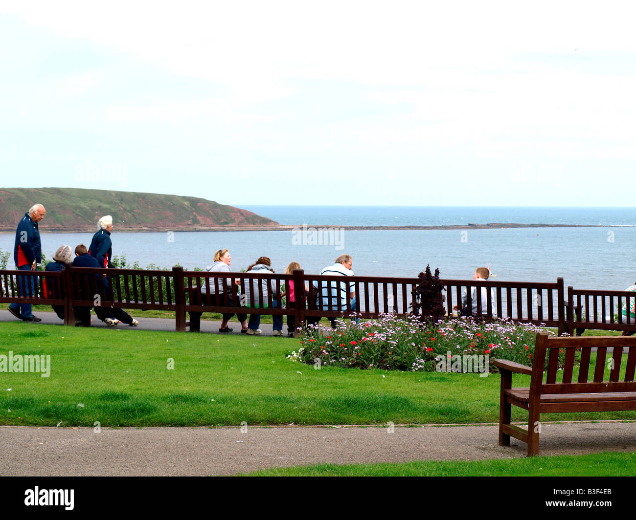 Visitors and holidaymakers,relax,looking over Filey bay towards 'Filey brigg'at Filey,North Yorkshire,England,uk. Stock Photo