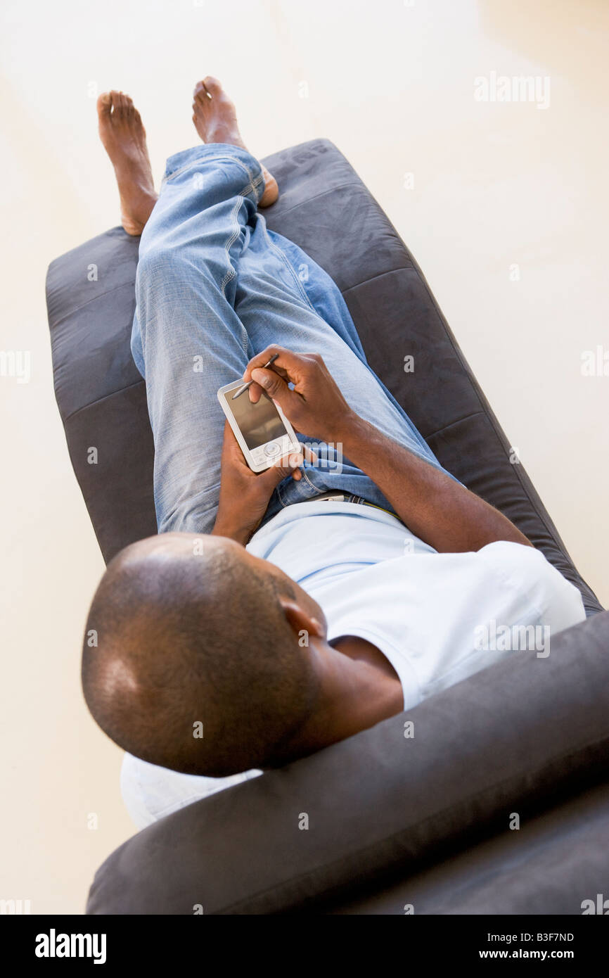 Man sitting in chair using personal digital assistant Stock Photo