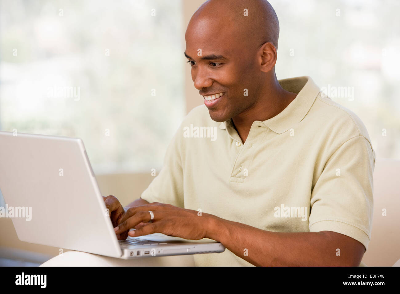Man in living room using laptop and smiling Stock Photo