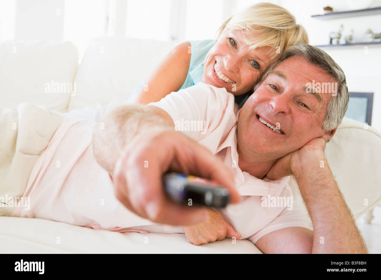Couple in living room using remote control smiling Stock Photo