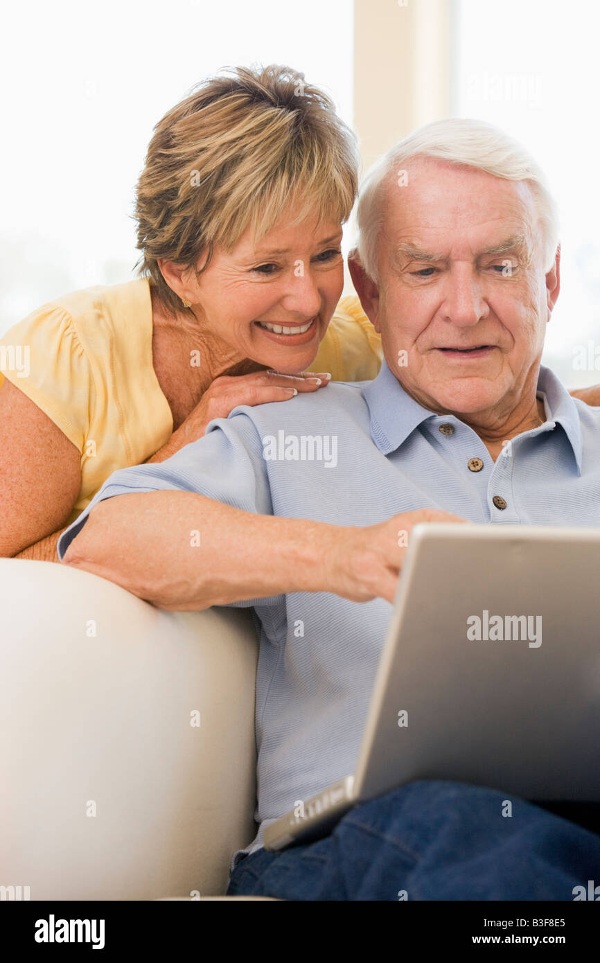 Couple in living room with laptop smiling Stock Photo - Alamy