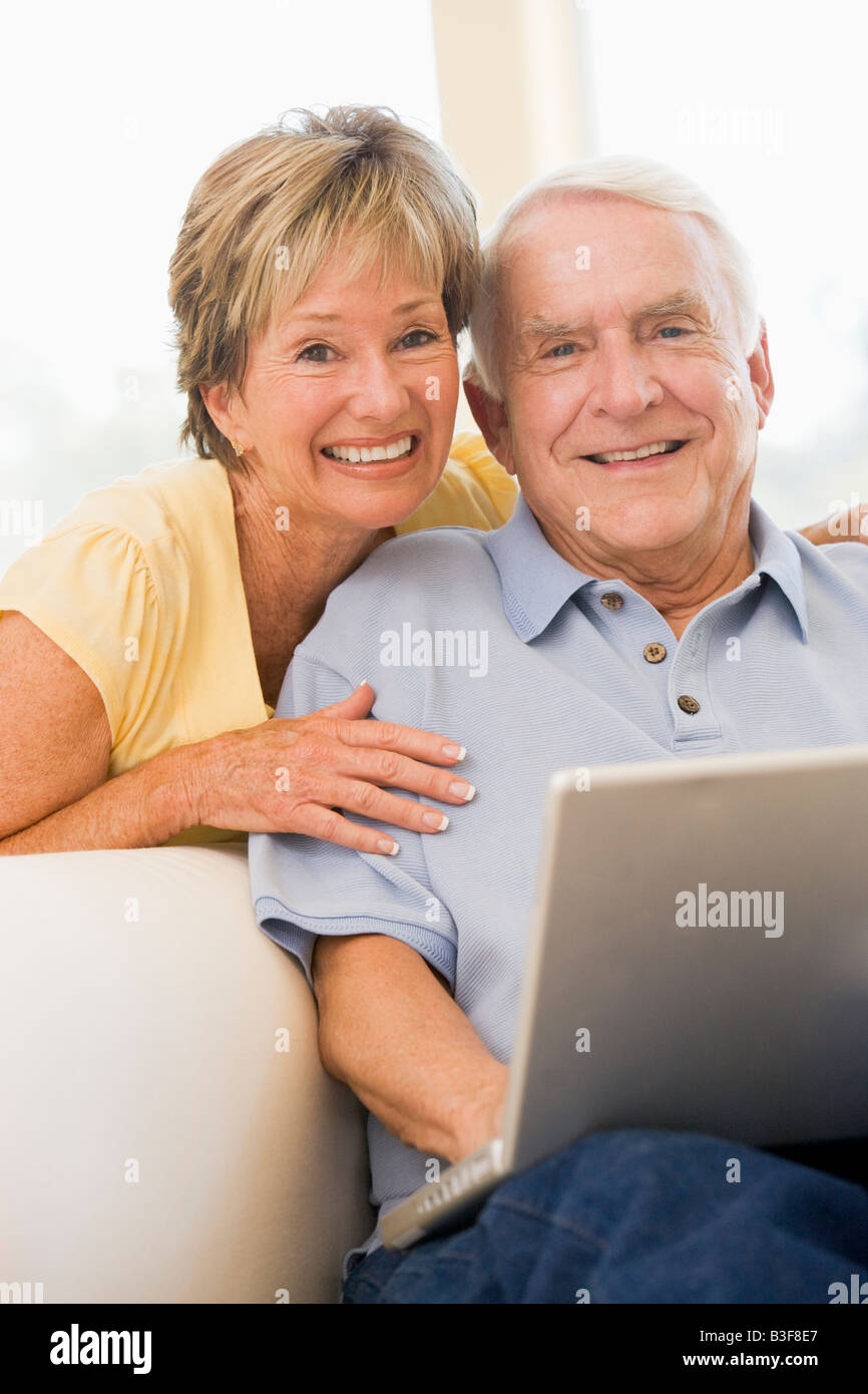 Couple in living room with laptop smiling Stock Photo