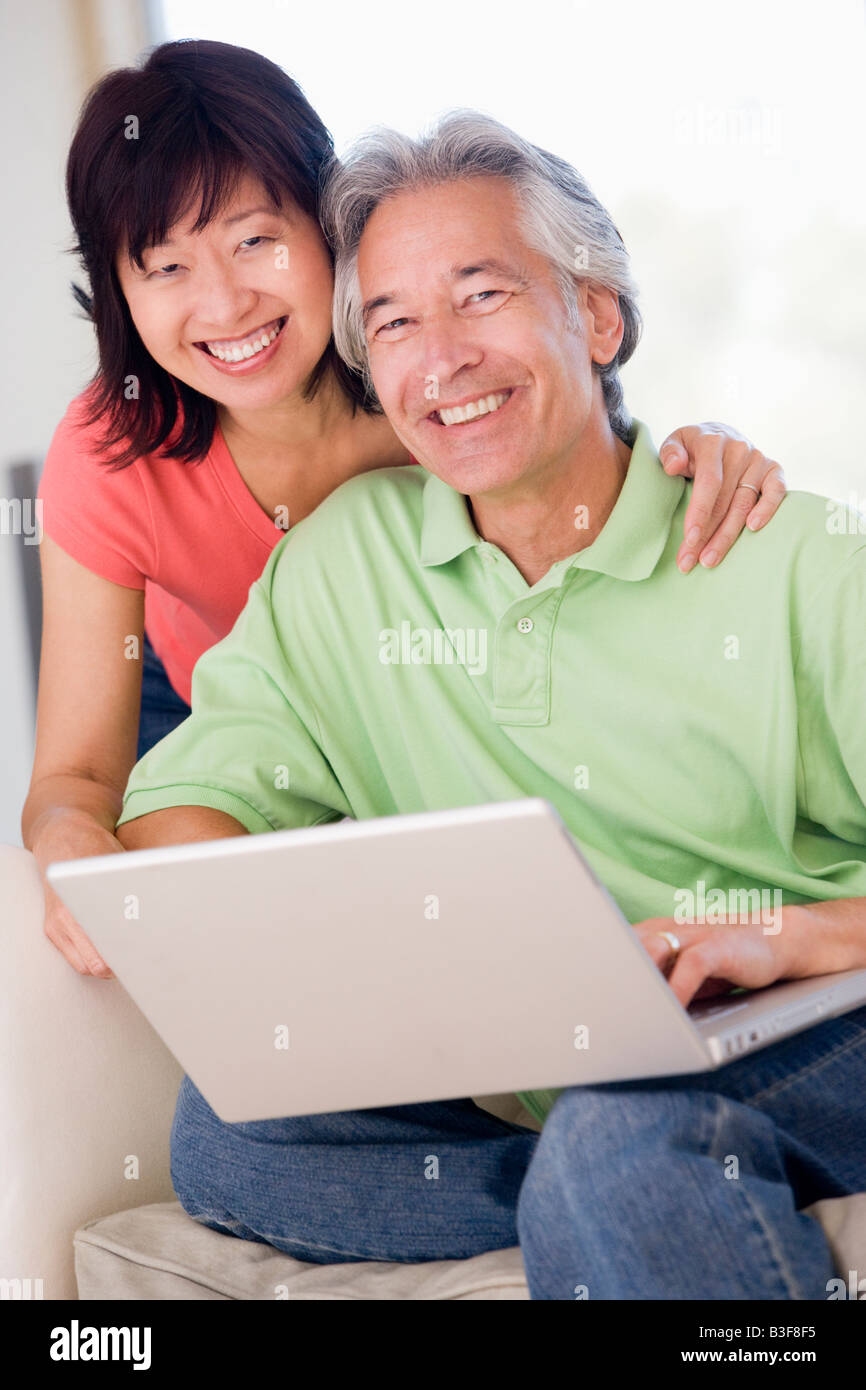 Couple in living room with laptop smiling Stock Photo - Alamy