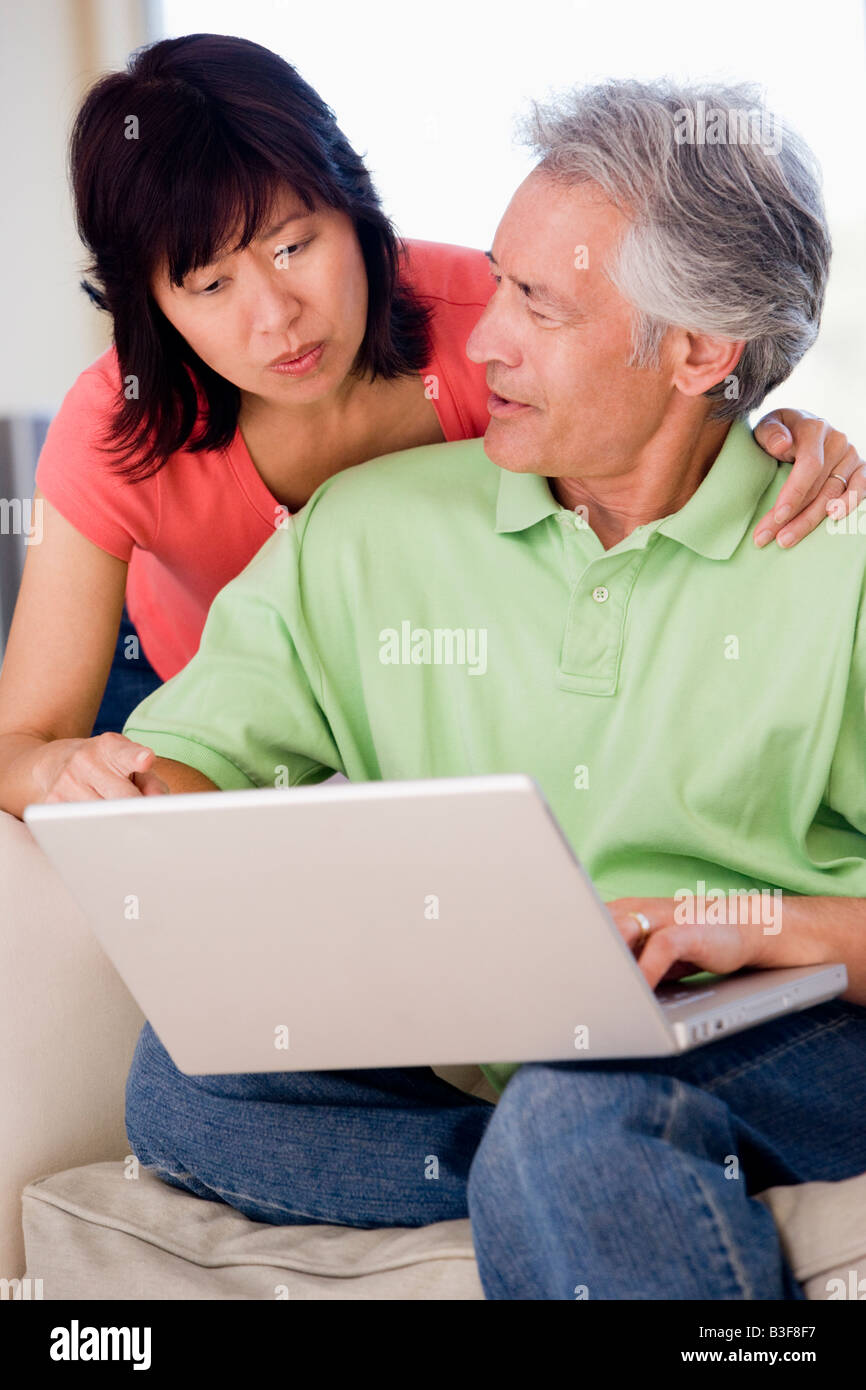 Couple in living room with laptop smiling Stock Photo - Alamy