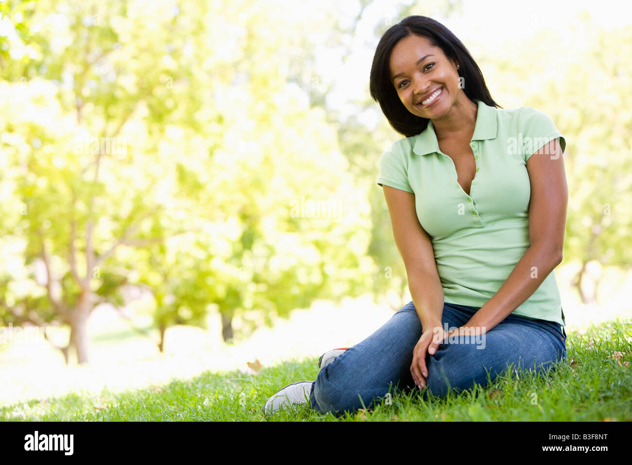 Woman sitting outdoors smiling Stock Photo - Alamy