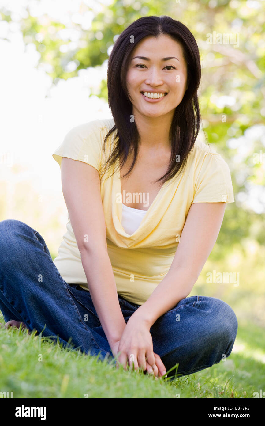 Woman sitting outdoors smiling Stock Photo - Alamy