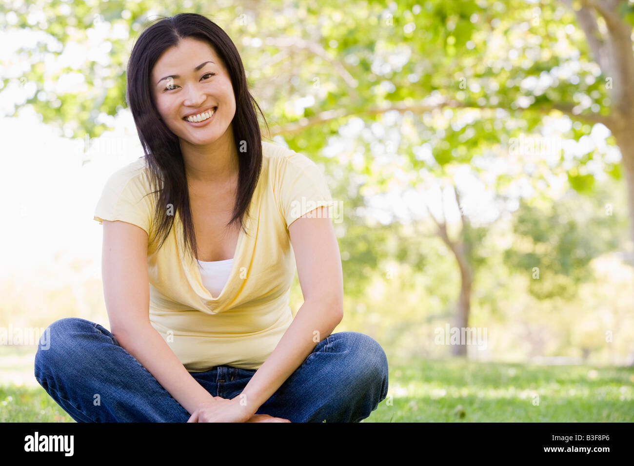 Woman sitting outdoors smiling Stock Photo - Alamy
