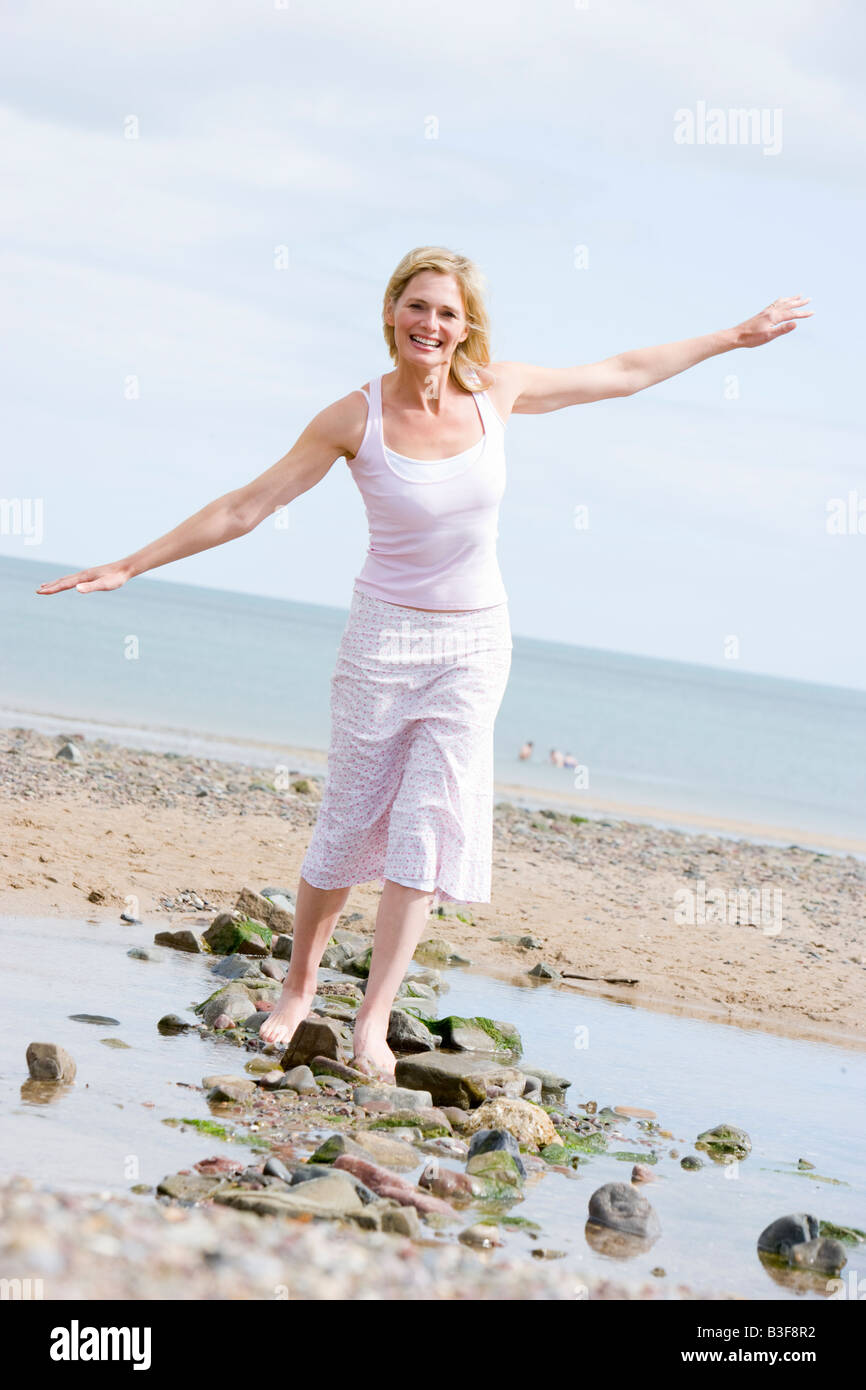 Woman walking on beach path smiling Stock Photo