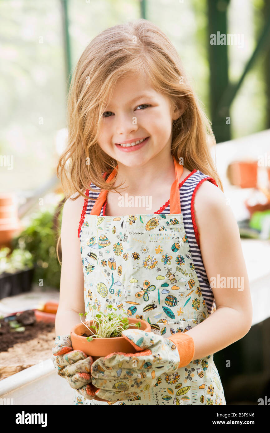 Young girl in greenhouse holding potted plant smiling Stock Photo - Alamy