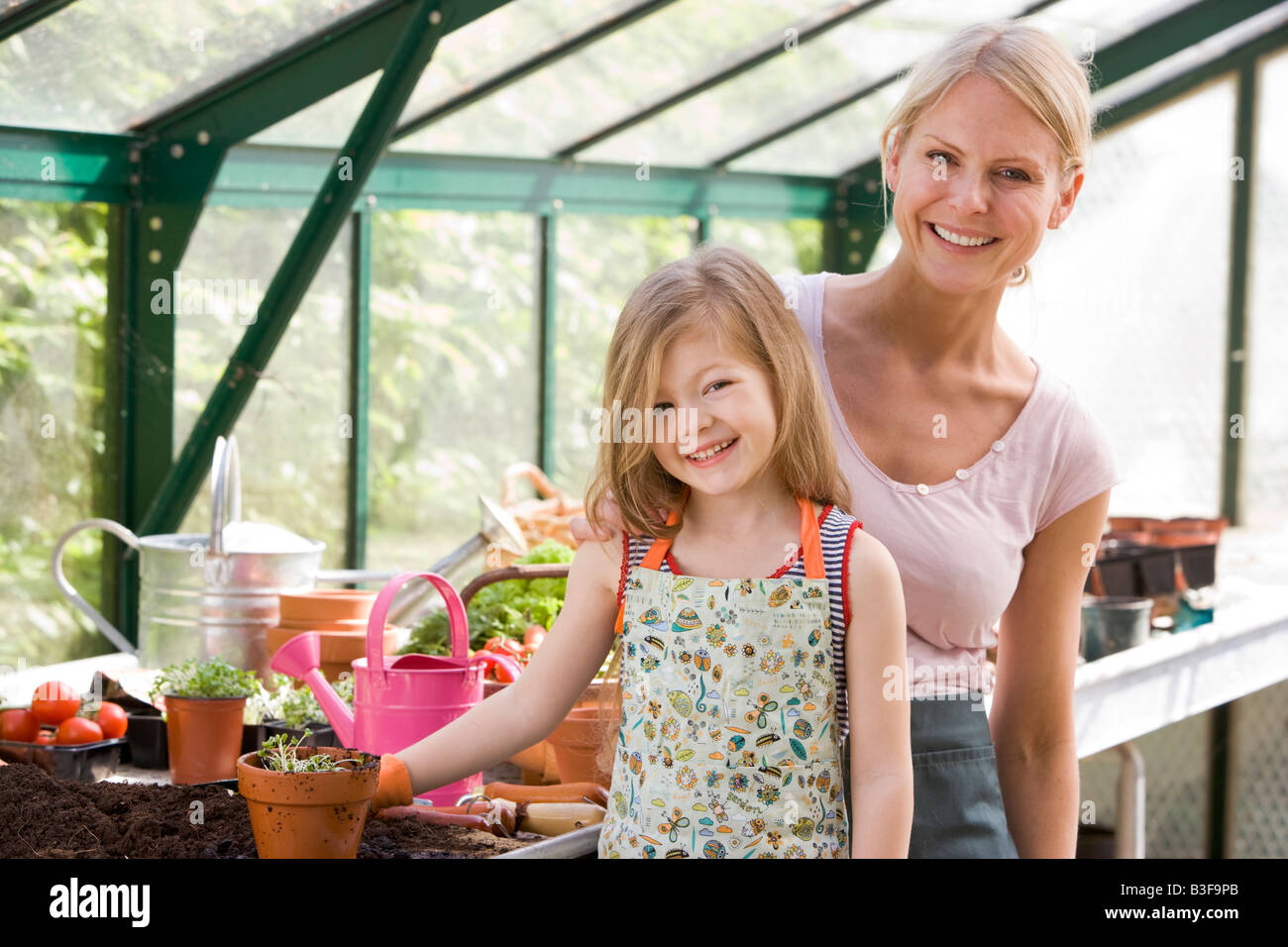 Young girl and woman in greenhouse smiling Stock Photo - Alamy