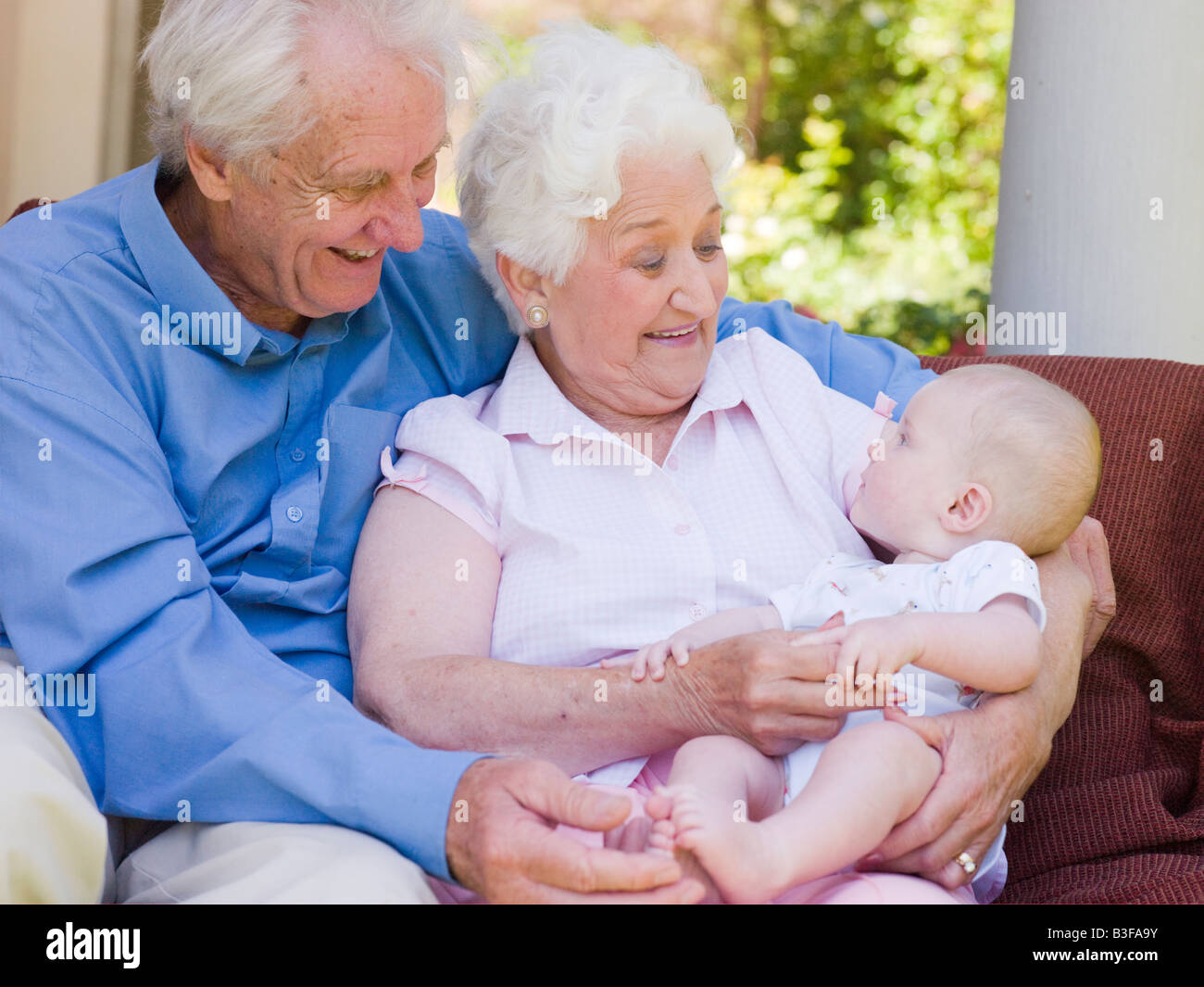 Grandparents outdoors on patio with baby smiling Stock Photo