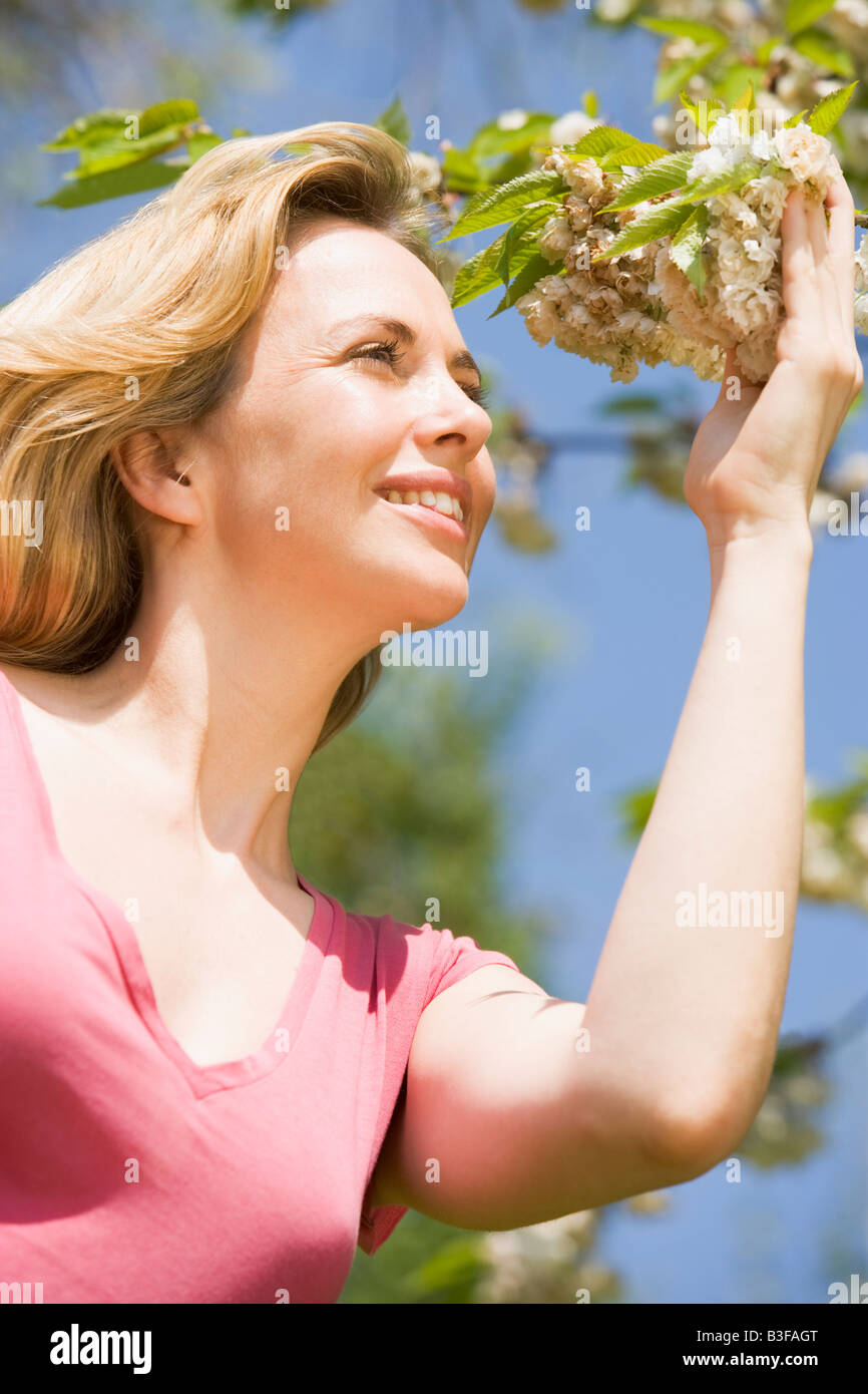Woman standing outdoors holding blossom smiling Stock Photo - Alamy